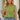 Woman wearing a green sleeveless top and denim shorts, holding a beige clutch.