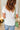 Person wearing a white t-shirt and blue jeans with a green handbag on a white background